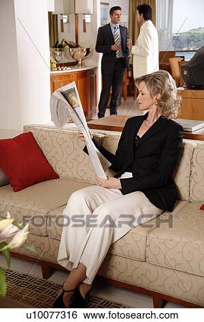 Stock Photograph - Bussinesswoman working reading newspaper during meeting. Fotosearch