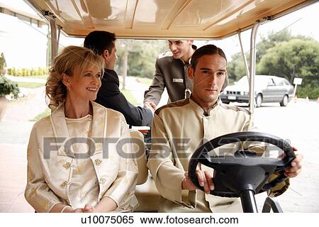 Stock Photography - Couple being driven in cart by hotel bellboy. Fotosearch
