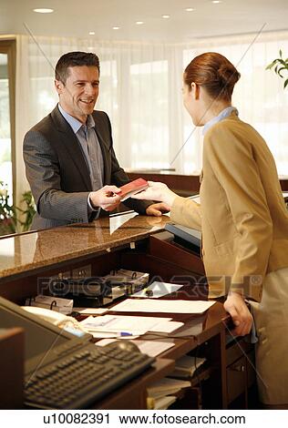 Stock Image - Man checking in at the hotel reception desk. Fotosearch