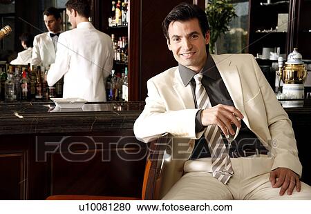 Stock Image - Man sitting at a bar drinking champagne. Fotosearch