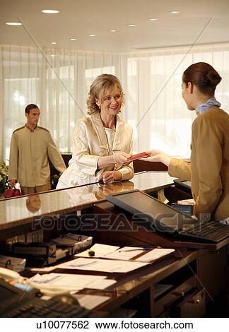 Woman checking in at the hotel reception desk View Large Photo Image Stock Image - Woman checking in at the hotel reception desk. Fotosearch