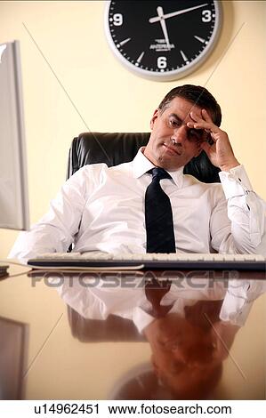 Businessman sitting at his desk lost in thought View Large Photo Image Stock Image - Businessman sitting at his desk lost in thought. Fotosearch