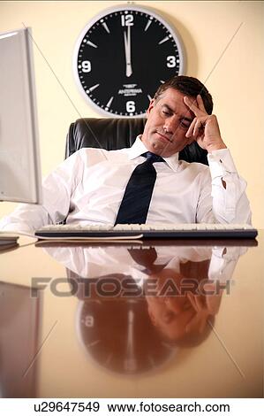 Businessman sitting at his desk lost in thought View Large Photo Image Stock Photo - Businessman sitting at his desk lost in thought. Fotosearch
