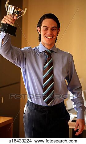 Picture - Young businessman holding trophy. Fotosearch