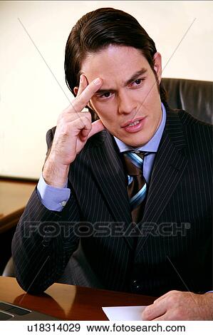Young businessman sitting at desk and thinking View Large Photo Image Stock Photo - Young businessman sitting at desk and thinking . Fotosearch