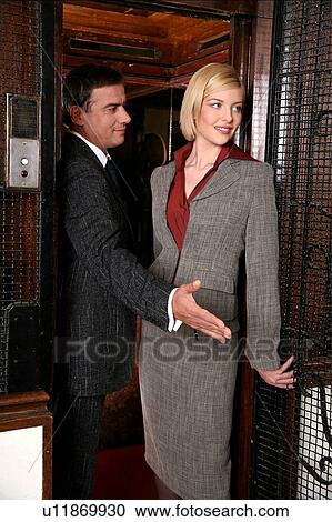 Stock Image -  Man and woman exiting from an elevator. Fotosearch