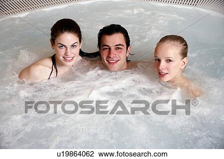 Stock Image - One man with two woman in jacuzzi at a spa. Fotosearch