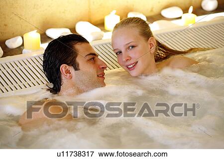 Stock Photo - One man with two woman in jacuzzi at a spa. Fotosearch