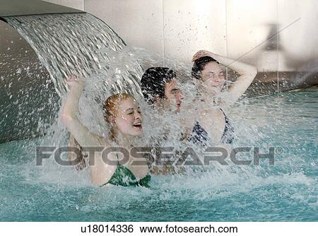 Young people standing under water spray in spa pool View Large Photo Image Stock Photograph - Young people standing under water spray in spa pool. Fotosearch