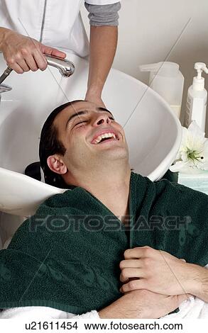 Picture - Young man having his hair washed at a salon. Fotosearch