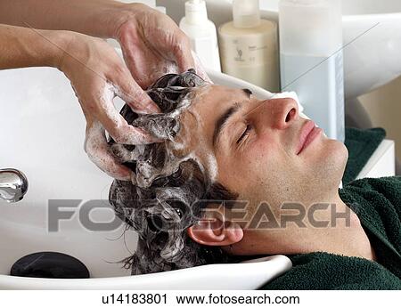 Stock Image - Young man having his hair washed at a salon. Fotosearch