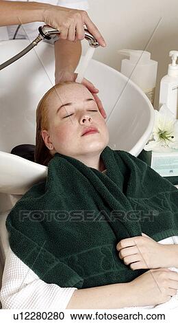 Stock Image - Young woman having her hair washed at a salon. Fotosearch