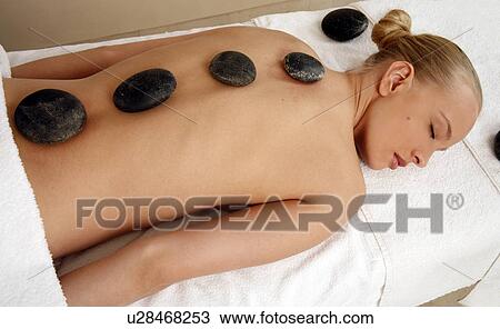 Stock Image - Young woman enjoying a hot stone massage. Fotosearch