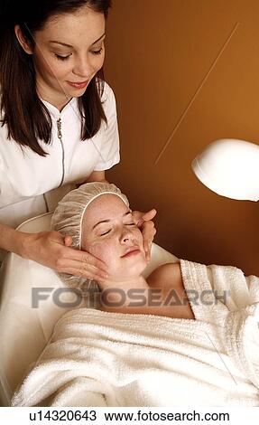 Stock Image - Woman having a facial treatment at a spa. Fotosearch