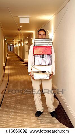 Stock Image - Bellboy carrying gift boxes down hallway. Fotosearch