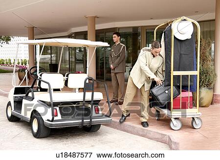 Bellboy delivering luggage to hotel with doorman standing by View Large Photo Image Stock Photo - Bellboy delivering luggage to hotel with doorman standing by. Fotosearch
