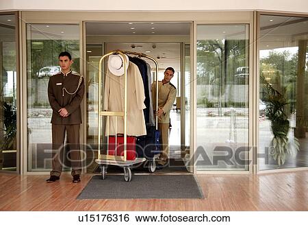 Bellboy delivering luggage to hotel with doorman standing by View Large Photo Image Stock Photograph - Bellboy delivering luggage to hotel with doorman standing by. Fotosearch