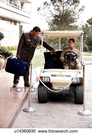 Bellboy driving hotel cart to deliver luggage to doorman View Large Photo Image Stock Image - Bellboy driving hotel cart to deliver luggage to doorman. Fotosearch