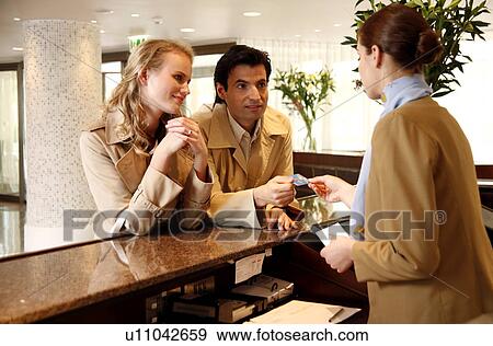 Couple checking in at hotel reception View Large Photo Image Stock Photo - Couple checking in at hotel reception. Fotosearch