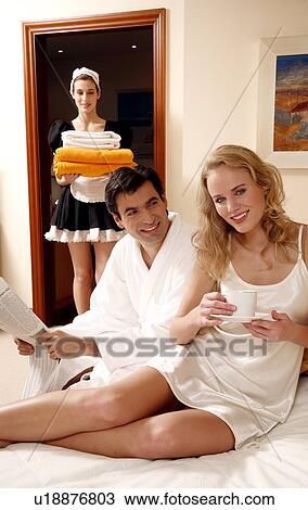 Stock Image - Couple on bed in hotel room. Fotosearch