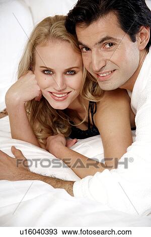 Stock Image - Couple relaxing in bed. Fotosearch