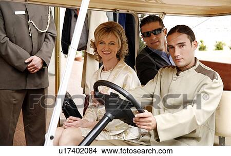 Picture - Couple being driven in cart by hotel bellboy. Fotosearch