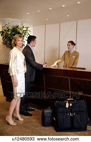 Couple checking in at hotel reception View Large Photo Image Stock Image - Couple checking in at hotel reception. Fotosearch