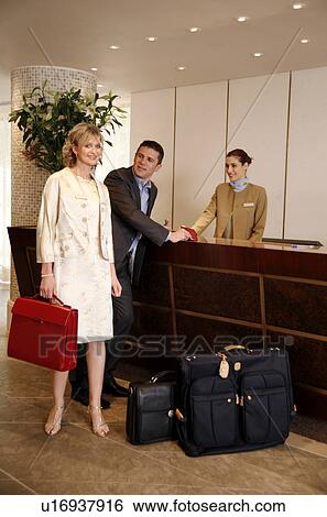 Stock Photograph - Couple checking in at hotel reception. Fotosearch