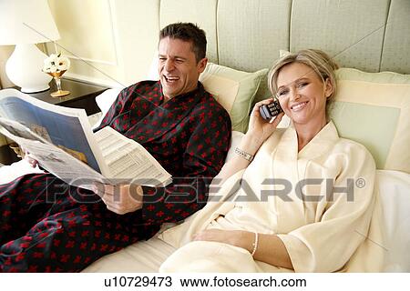 Stock Image - Mature couple relaxing in bed. Fotosearch