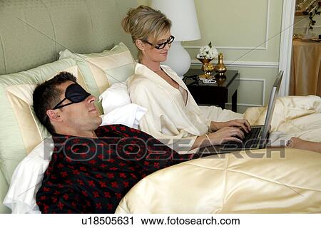 Stock Image - Mature couple relaxing in bed. Fotosearch