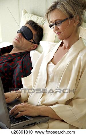 Stock Image - Mature couple relaxing in bed. Fotosearch