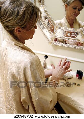 Woman sitting at the dressing table and putting on a ring View Large Photo Image Stock Image - Woman sitting at the dressing table and putting on a ring. Fotosearch