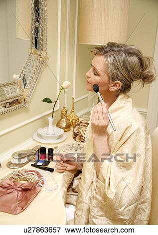 Woman sitting at the dressing table and applying cosmetics View Large Photo Image Stock Photo - Woman sitting at the dressing table and applying cosmetics. Fotosearch