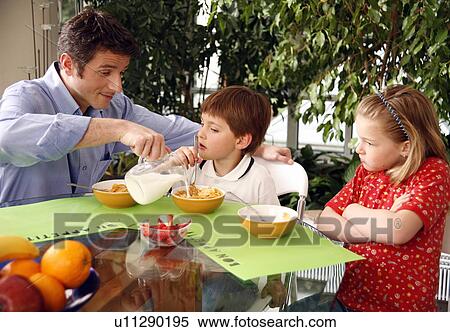 Stock Photography - Man eating breakfast and talking on cell phone. Fotosearch