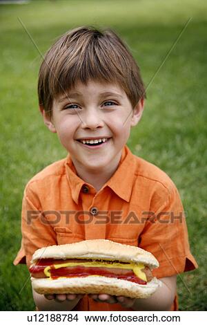 Little boy holding a hot dog View Large Photo Image Picture - Little boy holding a hot dog. Fotosearch