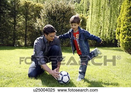 Stock Photography - Man teaching boy to play soccer. Fotosearch
