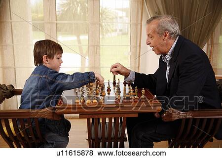 Stock Photo - Mature man and little boy playing chess. Fotosearch