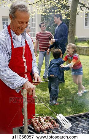 Mature man cooking food at a barbecue View Large Photo Image Stock Photo - Mature man cooking food at a barbecue. Fotosearch