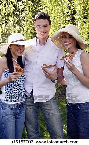 Stock Image - Three friends eating pizza. Fotosearch