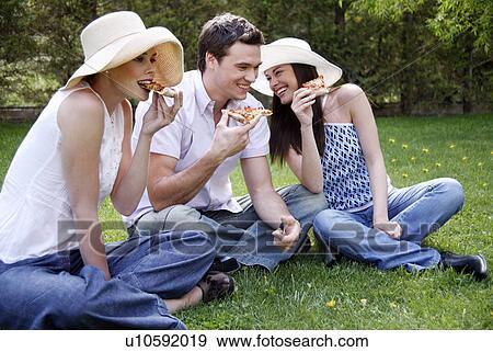 Three friends eating pizza View Large Photo Image Stock Photo - Three friends eating pizza. Fotosearch