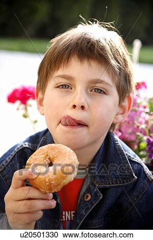 Stock Image - Young boy eating a doughnut. Fotosearch