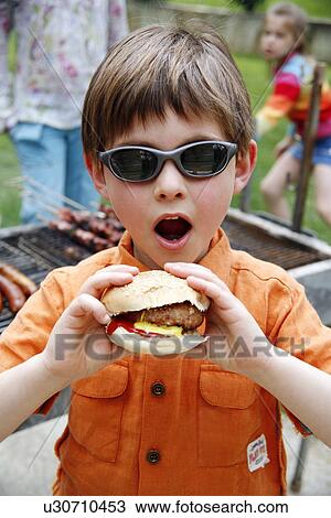 Stock Image - Young boy eating a hamburger. Fotosearch