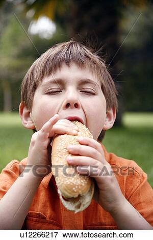 Stock Photo - Young boy eating a hot dog. Fotosearch