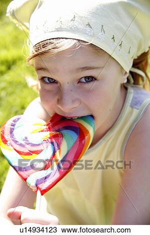 Stock Image - Young girl licking a lollipop. Fotosearch
