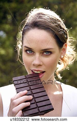 Stock Image - Young woman eating chocolate. Fotosearch