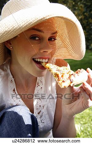Stock Image - Young woman eating pizza. Fotosearch
