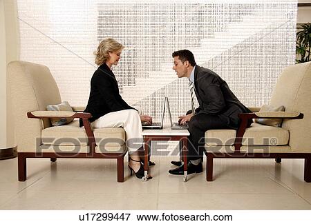 Stock Photo - Man and woman sitting in hotel lobby. Fotosearch