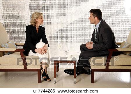 Stock Photograph - Man and woman sitting in hotel lobby. Fotosearch