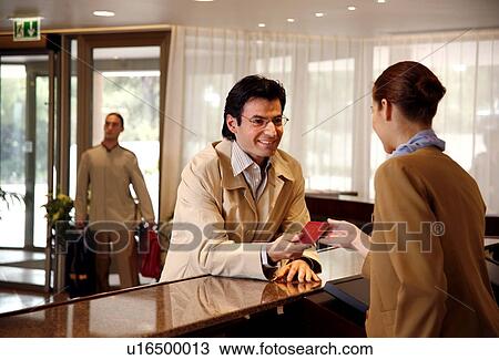Stock Image - Man checking in at the hotel reception desk. Fotosearch