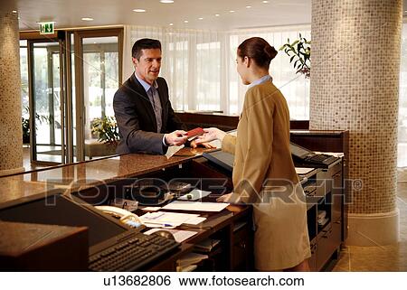 Stock Photograph - Man checking in at the hotel reception desk. Fotosearch